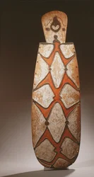 Ovalt Asmat-skjold, udskåret i relief med stiliserede figurer, en maske øverst (træ)