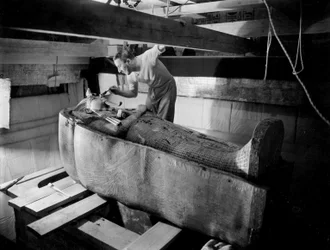 Opdagelsen af farao Tutankhamons grav i Kongernes Dal (Egypten): i gravkammeret arbejder Howard Carter på låget til den anden kiste, oktober 1925, foto af Harry Burton (p1568)