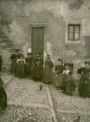 Kvinder og børn iført traditionelt tøj på trappen op til et hus, Abruzzo, Italien