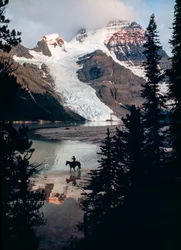 En enlig hest og rytter reflekterer over søen ved foden af Canadas højeste bjerg. Mount Robson...