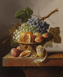 Druer, en appelsin og valnødder i en flettet kurv med en citron og blommer, alt sammen på en marmorkant