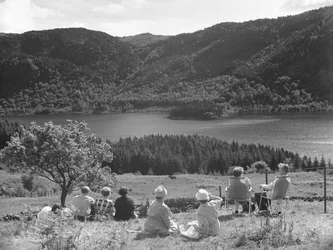 Gruppe af mennesker, der sidder på græs eller i liggestole og kigger på udsigten over Thirlmere