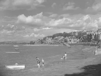 Folk leger i både ved højvande i Arnside med Albion Hotel i baggrunden