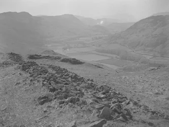 Udsigt over en åben dal ved Hardknott med bunker af sten i forgrunden