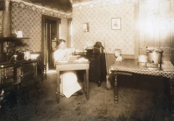 Kvinde indsætter børster i tandbørster i sit køkken, ca. 1912