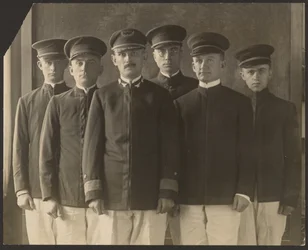 [Gruppe af unge mænd i uniform foran billedtæppe (kadetter)].