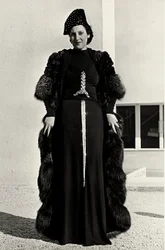 Model i aftenkjole skabt af det italienske couture-hus "Dragoni". Artiklens skrifttype har en prangende pailletdekoration i form af et sværd. En hat og pelsoverfrakke fuldender ensemblet. (s/h foto)