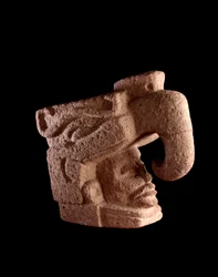 Præcolumbiansk kunst, mayacivilisationen, den præklassiske periode: stenskulptur, der forestiller et mandshoved, som stiger op fra munden på en zoomorf gud, der ligner den himmelske fugl. 38 x 46 cm. Guatemala, Museo Nacional de Arqueología y Etnología