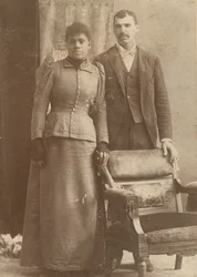 Fotografi af et afroamerikansk par, der står bag en stol, ca. 1890.