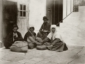 Kvinder maler mel med runde møllesten i en gårdhave til et hus i Jerusalem, 1867