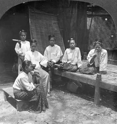 Burmesiske kvinder, der ryger uden for deres hjem, Mandalay, Burma, 1908.
