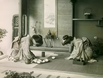 To japanske kvinder i traditionelle dragter hilser på hinanden før teceremonien, ca. 1900 - 1915 (fotografi)