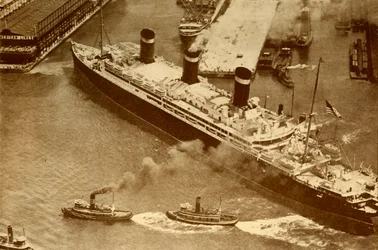 Et luftfoto af Leviathan, der bliver bugseret af små slæbebåde ind i hendes dok i New York, c1930