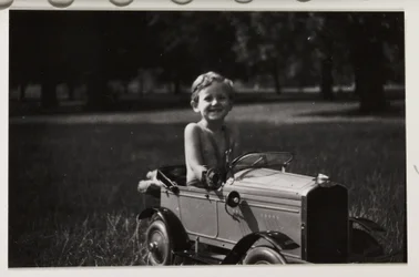 Dreng kører i en legetøjs-pedalbil, ca 1930