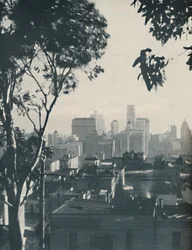 Boliger af beskedent træ i skyggen af betongiganter, ca. 1935