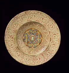Maiolica tallerken dekoreret med et kunstfærdigt gentagne knudedesign, der rammer profilhoveder på kanten og et skjold i den centrale plakette, italiensk, lavet i Toscana