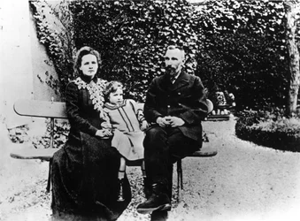 Pierre (1859-1906) og Marie Curie (1867-1934) sidder på en bænk i en have.