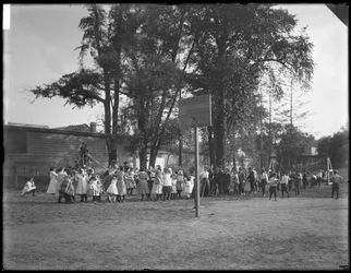 Drenge og piger leger tovtrækkeri på en uidentificeret legeplads, ca. 1910