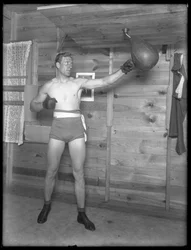 Den engelske bokser William Thomas Wells (Bombardier Billy Wells), poserer i træningsbukser med en speedbag, ca. 1911.