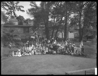 Stor gruppe børn samlet til et gruppeportræt på en uidentificeret legeplads, ca. 1910