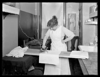 Uidentificeret kvinde demonstrerer brugen af et elektrisk strygejern ca. 1913-14