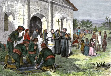 Spansk mission i Californien med præster, soldater og amerikanske indianere, der beder foran kirken i det 18. århundrede.