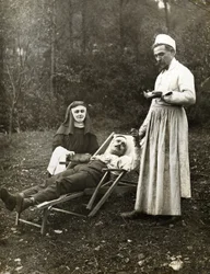Læge tager pulsen på en såret mand, assisteret af en sygeplejerske nonne, omkring 1900 (s/h foto)